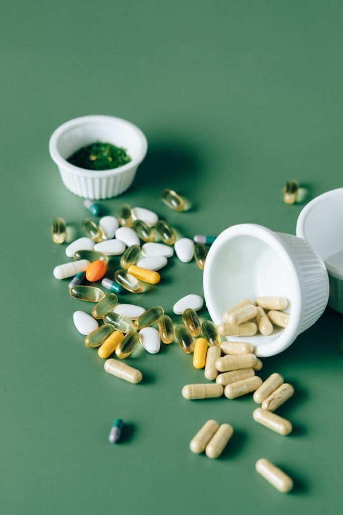 Variety of supplements and pills scattered on a green background, showcasing modern medicine concepts.